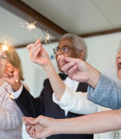 Un gruppo di persone canta Tanti auguri con in mano delle stelle filanti