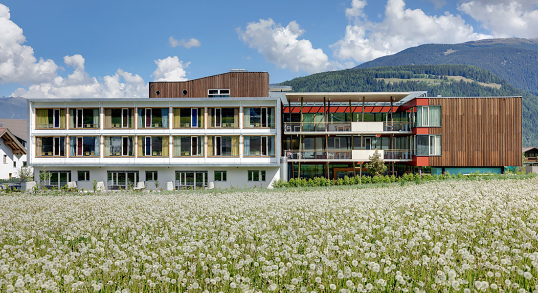 Un prato pieno di fiori davanti al centro residenziale di cura Valdora; sullo sfondo si vedono le montagne